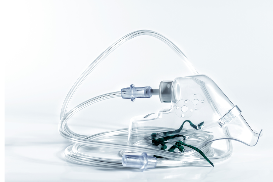 A transparent plastic mask designed for delivering aerosolized medication, attached to a nebulizer tube.